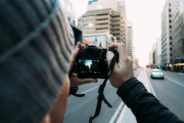 Person fotografiert eine urbane Straßenszene mit einer Kamera, Fokus auf Kreativität in der Stadtfotografie.