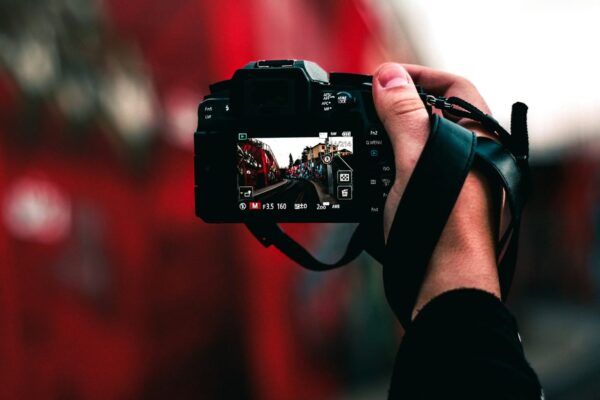 Hand hält DSLR-Kamera, die eine Straßenansicht mit Graffiti im Sucher zeigt.