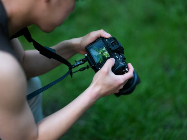 Fotograf mit DSLR-Kamera und Kameragurt in der Natur